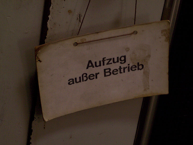 stained cardboard sign “Aufzug außer Betrieb” hanging from aged lift out of service; photo